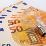 Energiepreise - 50 Euro Scheine liegen aufgefächert, Glühbirne liegt darauf