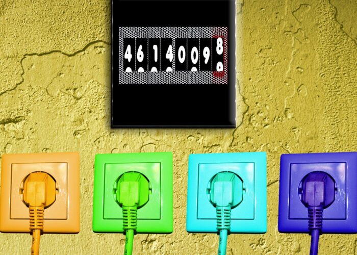 Stromzähler, der Stromverbrauch misst. Darunter befinden sich vier Steckdosen mit Steckern in Orange, Grün, Blau und Lila